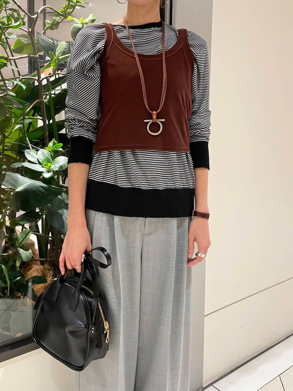 ブラック系のショルダーバッグ、ホワイト系のニット/セーター、グレー系のその他パンツを着用したレディースの秋コーディネートの5枚目の写真