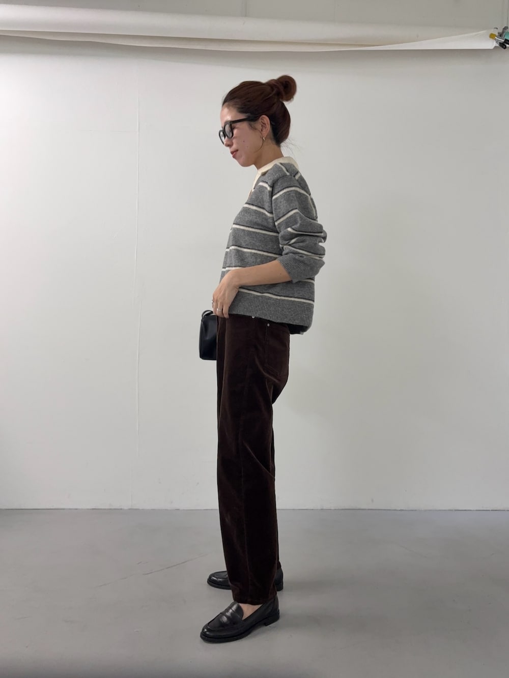 グレー系のニット/セーター、ブラウン系のその他パンツ、ブラック系のハンドバッグを着用したレディースの秋コーディネートの2枚目の写真