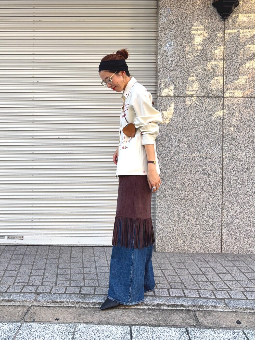 ホワイト系のTシャツ/カットソー、ブラウン系のスカート、ブルー系のデニムパンツを着用したレディースの秋コーディネートの4枚目の写真