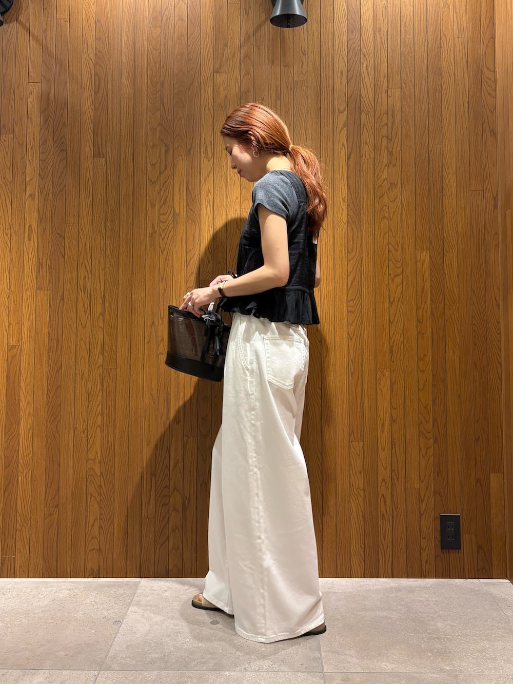ホワイト系のデニムパンツ、ベージュ系のサンダル、ブラック系のかごバッグを着用したレディースの夏コーディネートの2枚目の写真