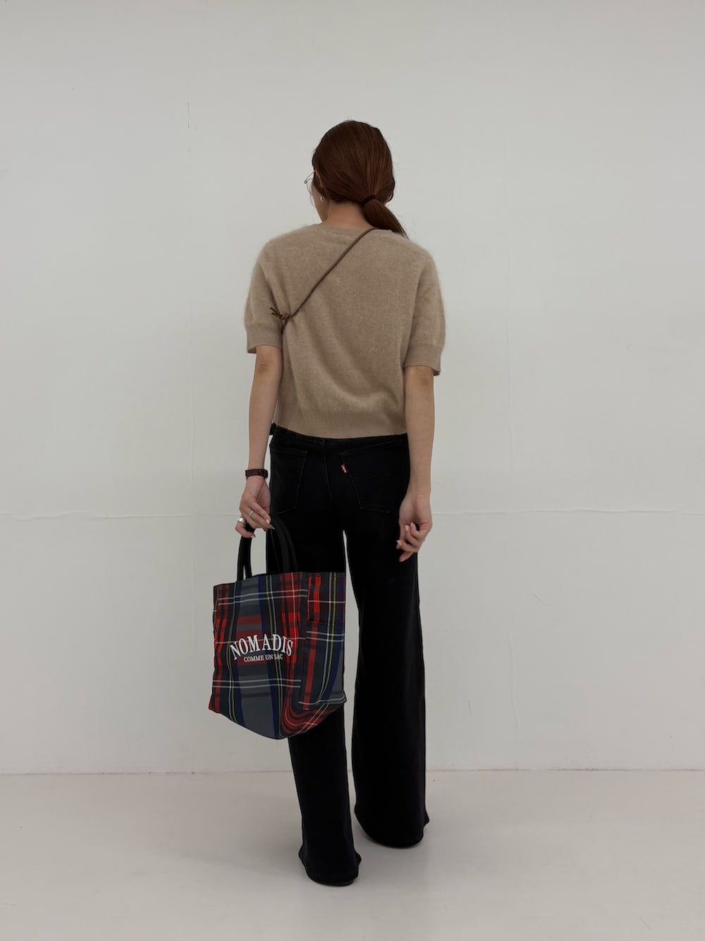 ブラック系のデニムパンツ、グレー系のトートバッグ、ベージュ系のニット/セーターを着用したレディースの夏コーディネートの3枚目の写真