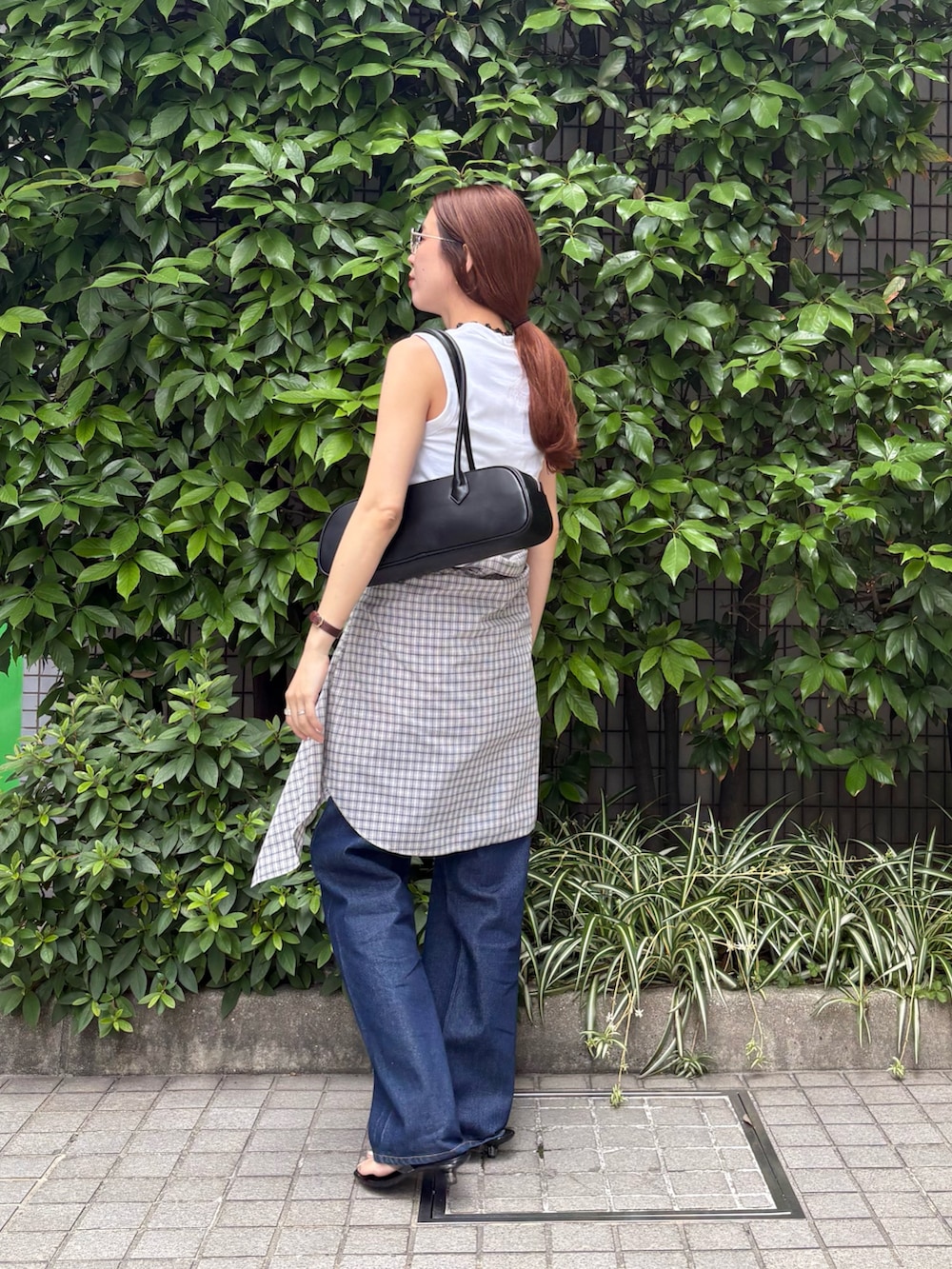 ブルー系のデニムパンツ、ブラック系のショルダーバッグ、ホワイト系のタンクトップを着用したレディースの夏コーディネートの3枚目の写真