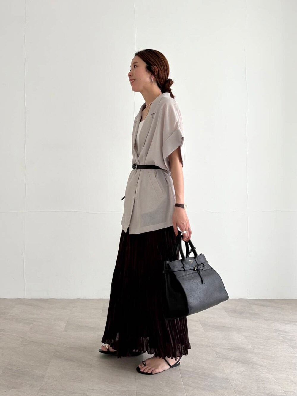 ホワイト系のキャミソール、ブラウン系のスカート、ブラック系のサンダルを着用したレディースの夏コーディネートの2枚目の写真