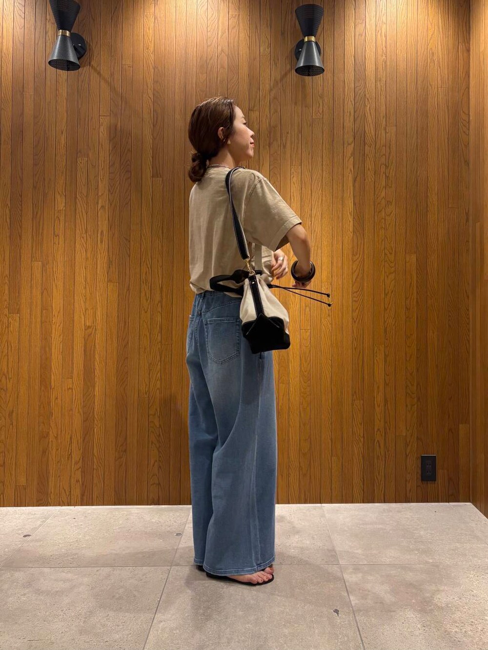 ブルー系のデニムパンツ、ブラック系のサンダル、ベージュ系のTシャツ/カットソーを着用したレディースの夏コーディネートの2枚目の写真