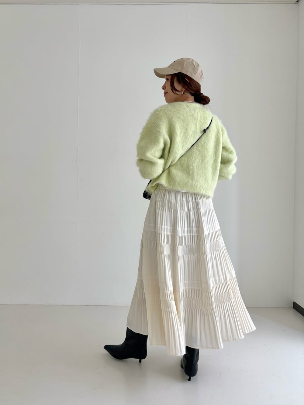 ホワイト系のスカート、グリーン系のカーディガン/ボレロ、ブラック系のブーツを着用したレディースの秋コーディネートの3枚目の写真