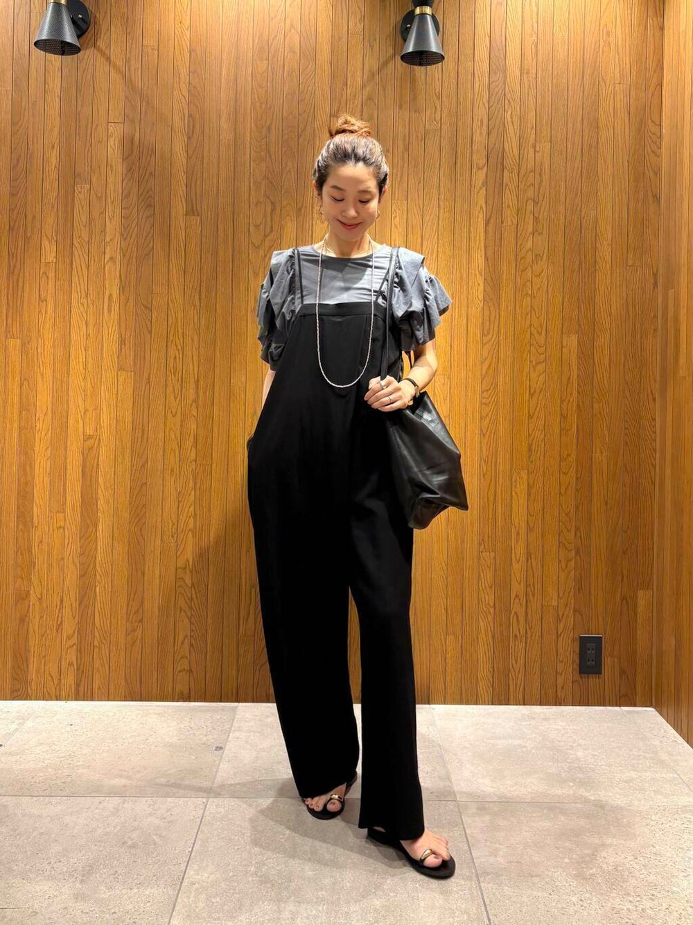 ブラック系のサロペット/オーバーオール、ブルー系のTシャツ/カットソー、ブラック系のサンダルを着用したレディースの夏コーディネートの5枚目の写真
