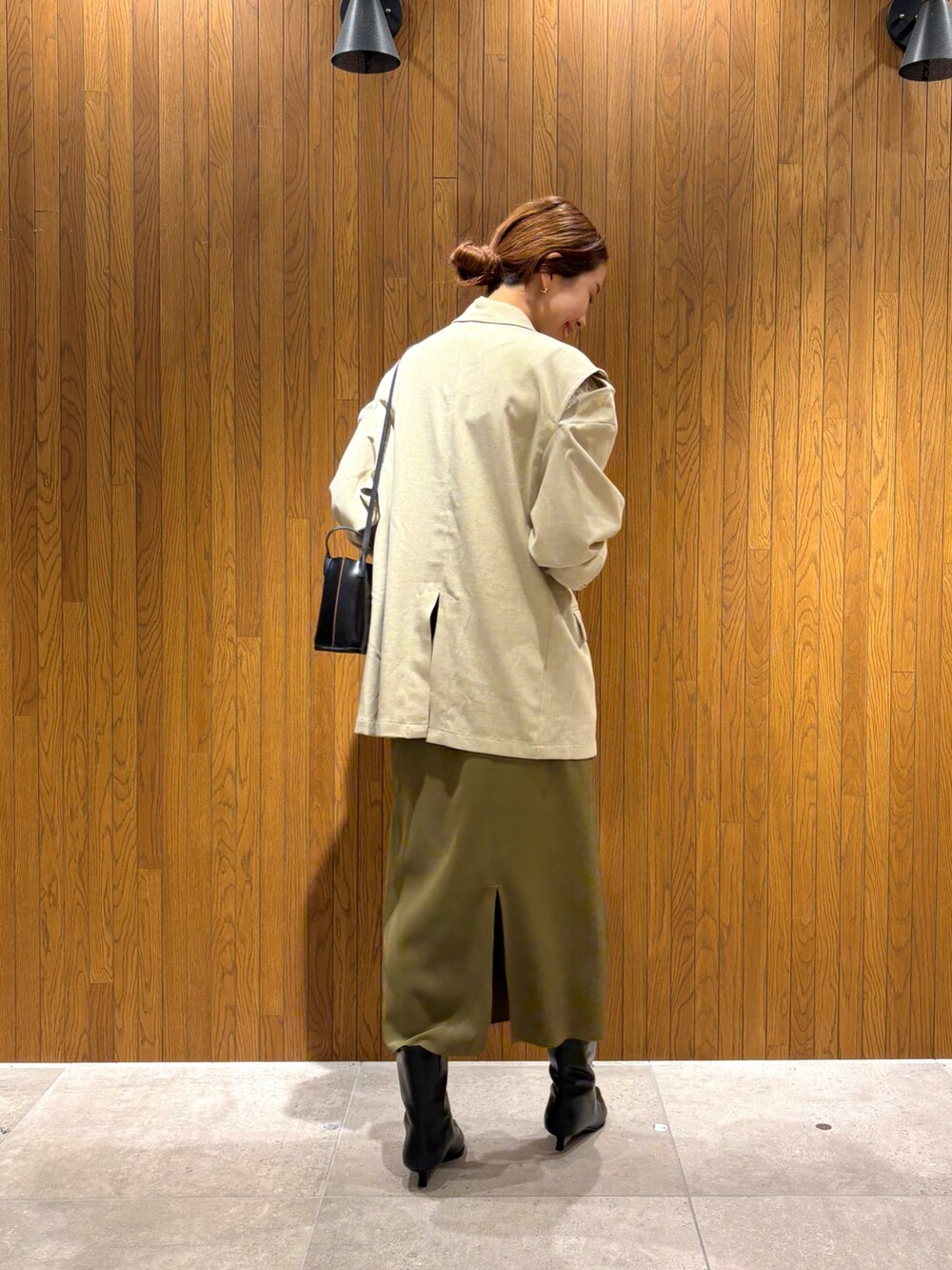 グリーン系のスカート、ブラック系のブーツ、ホワイト系のその他アウターを着用したレディースの秋コーディネートの3枚目の写真