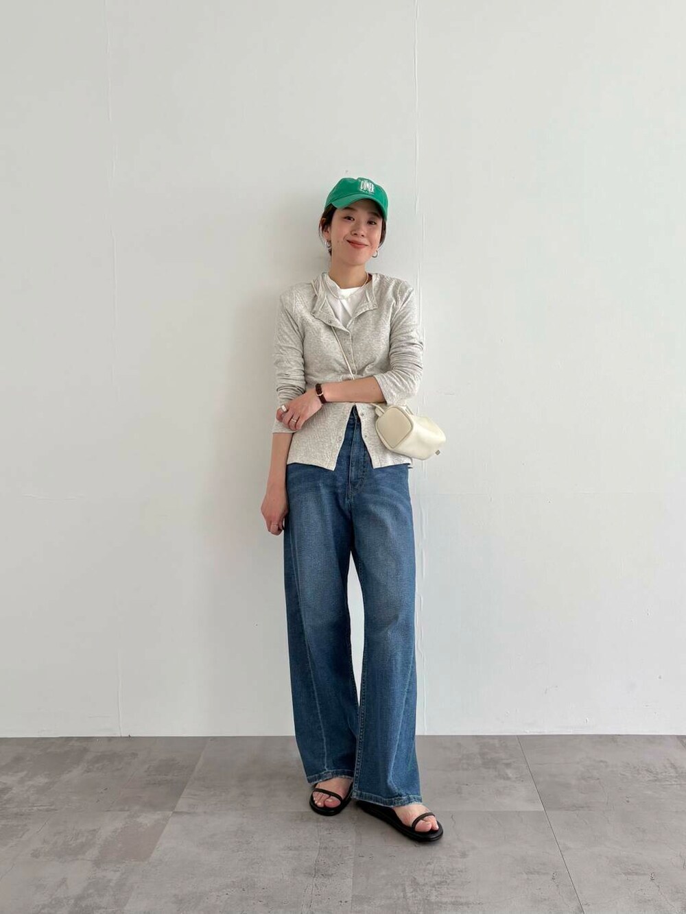 グレー系のカーディガン/ボレロ、ブルー系のデニムパンツ、ホワイト系のショルダーバッグを着用したレディースの春コーディネートの4枚目の写真