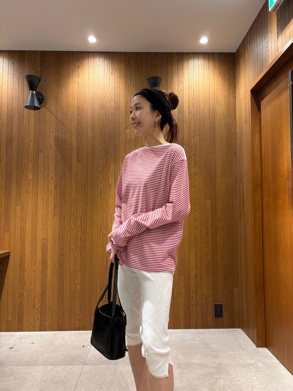 ベージュ系のその他アウター、レッド系のTシャツ/カットソー、ブラック系のハンドバッグを着用したレディースの春コーディネートの7枚目の写真