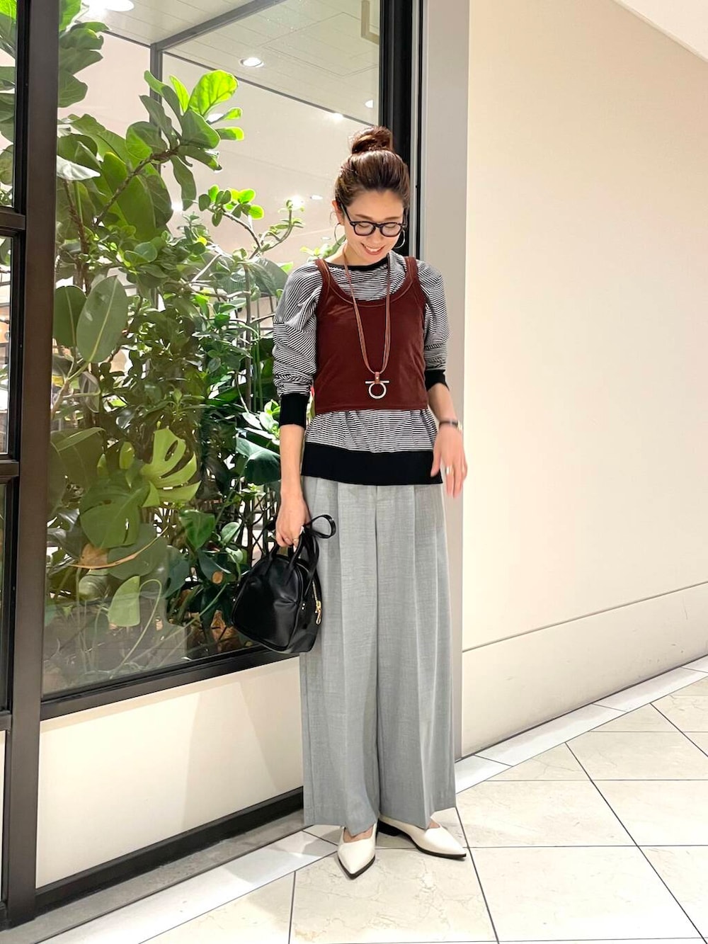 ブラック系のショルダーバッグ、ホワイト系のニット/セーター、グレー系のその他パンツを着用したレディースの秋コーディネートの2枚目の写真