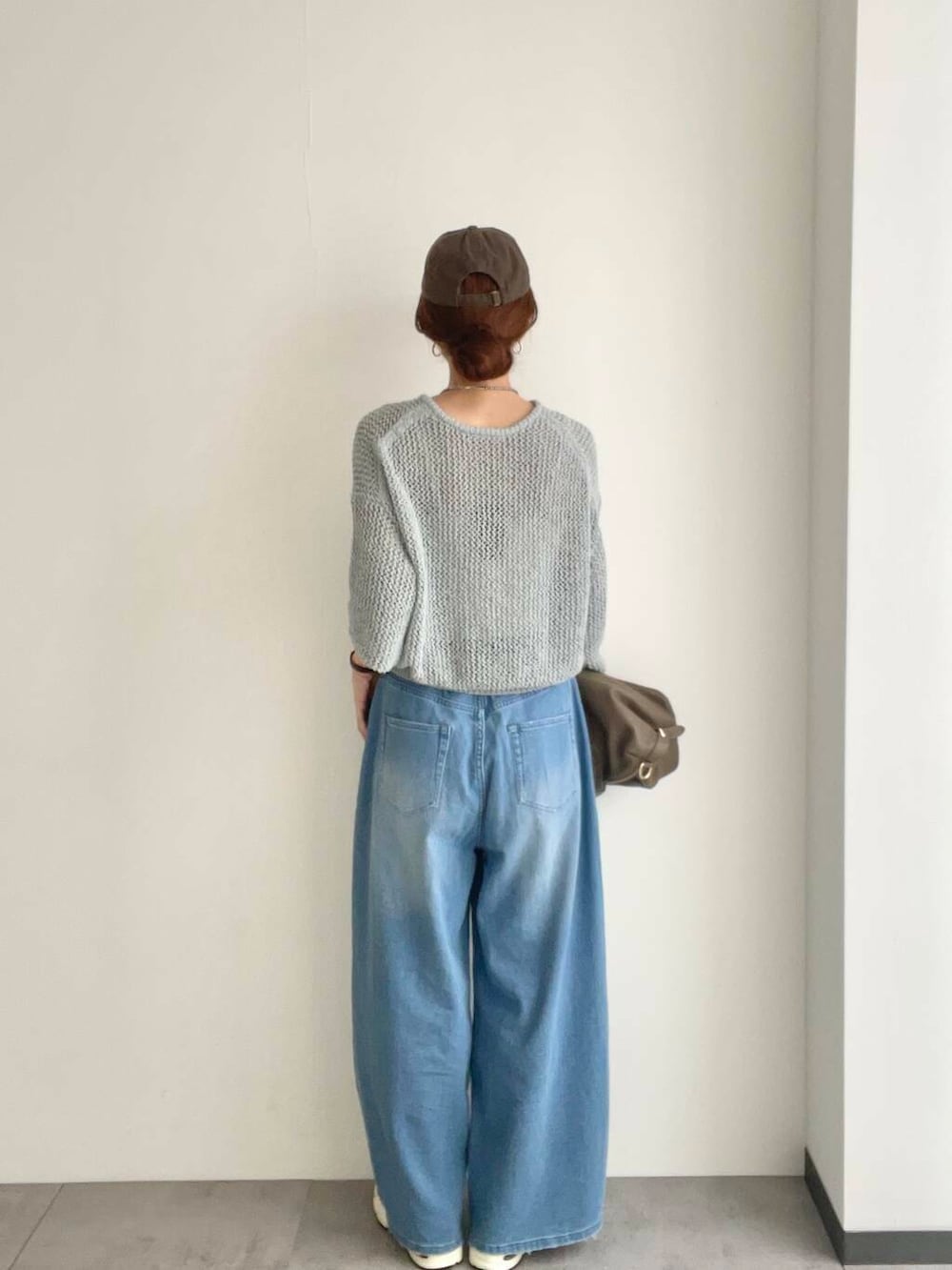 ベージュ系のボストンバッグ、グレー系のニット/セーター、ホワイト系のスニーカーを着用したレディースの春コーディネートの4枚目の写真