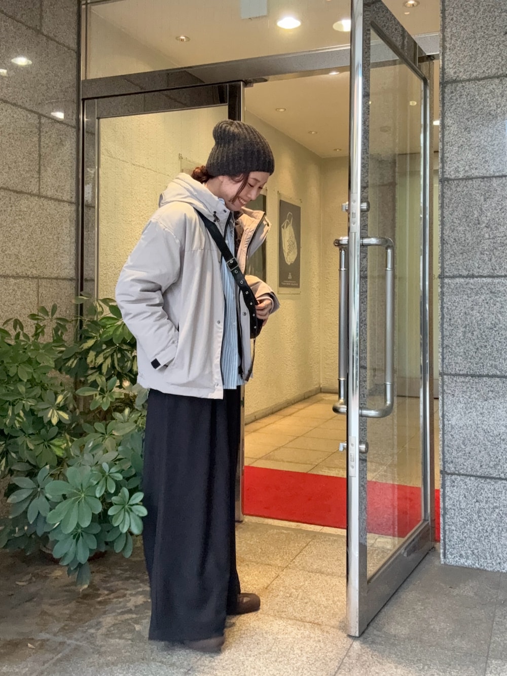 グレー系のダウンジャケット/コート、ブラック系のその他パンツ、ブラウン系のスニーカーを着用したレディースの秋コーディネートの4枚目の写真