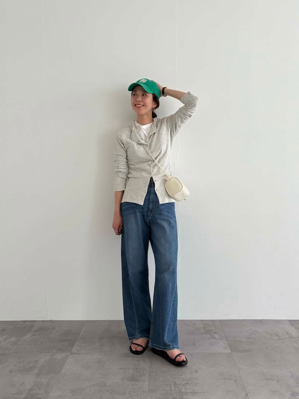 グレー系のカーディガン/ボレロ、ブルー系のデニムパンツ、ホワイト系のショルダーバッグを着用したレディースの春コーディネートの5枚目の写真