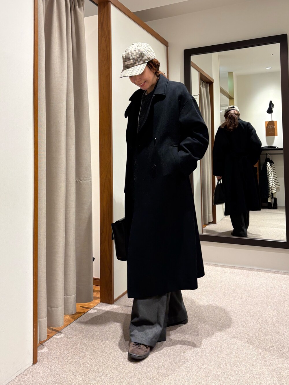 ブラック系のチェスターコート、グレー系のその他パンツ、ブラック系のハンドバッグを着用したレディースの冬コーディネートの4枚目の写真