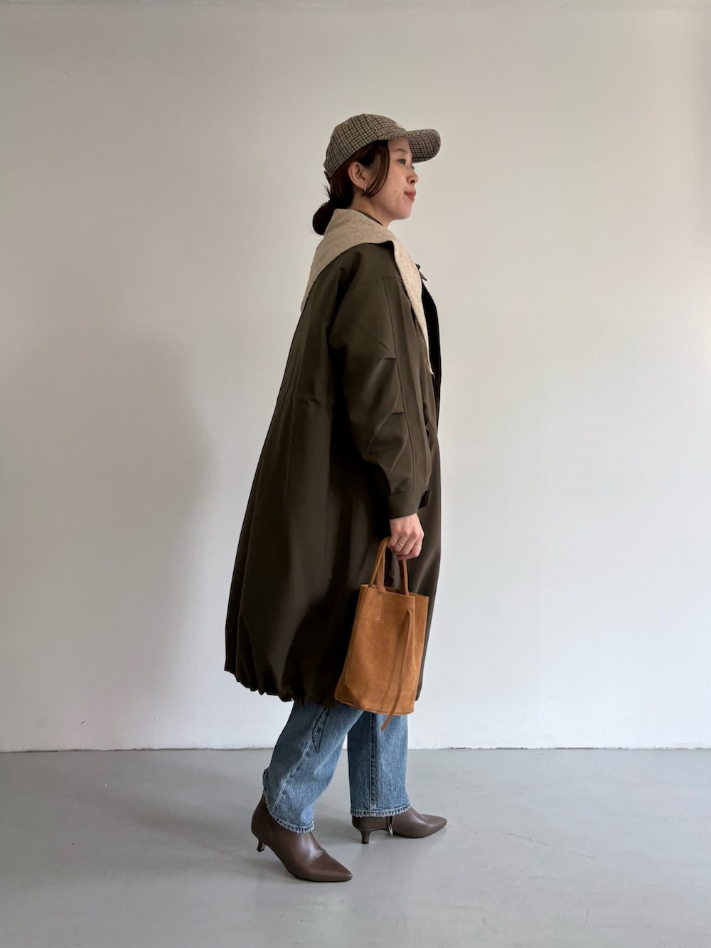 ブルー系のデニムパンツ、ベージュ系のトートバッグ、ホワイト系のTシャツ/カットソーを着用したレディースの冬コーディネートの3枚目の写真