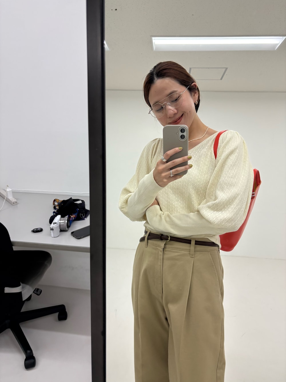 ホワイト系のニット/セーター、ベージュ系のその他パンツ、ブラック系のローファーを着用したレディースの夏コーディネートの9枚目の写真