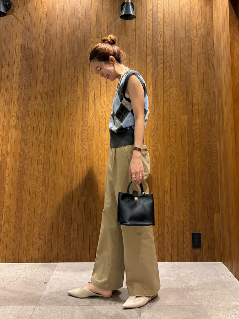 グレー系のベスト、ベージュ系のその他パンツ、ブラック系のハンドバッグを着用したレディースの夏コーディネートの3枚目の写真