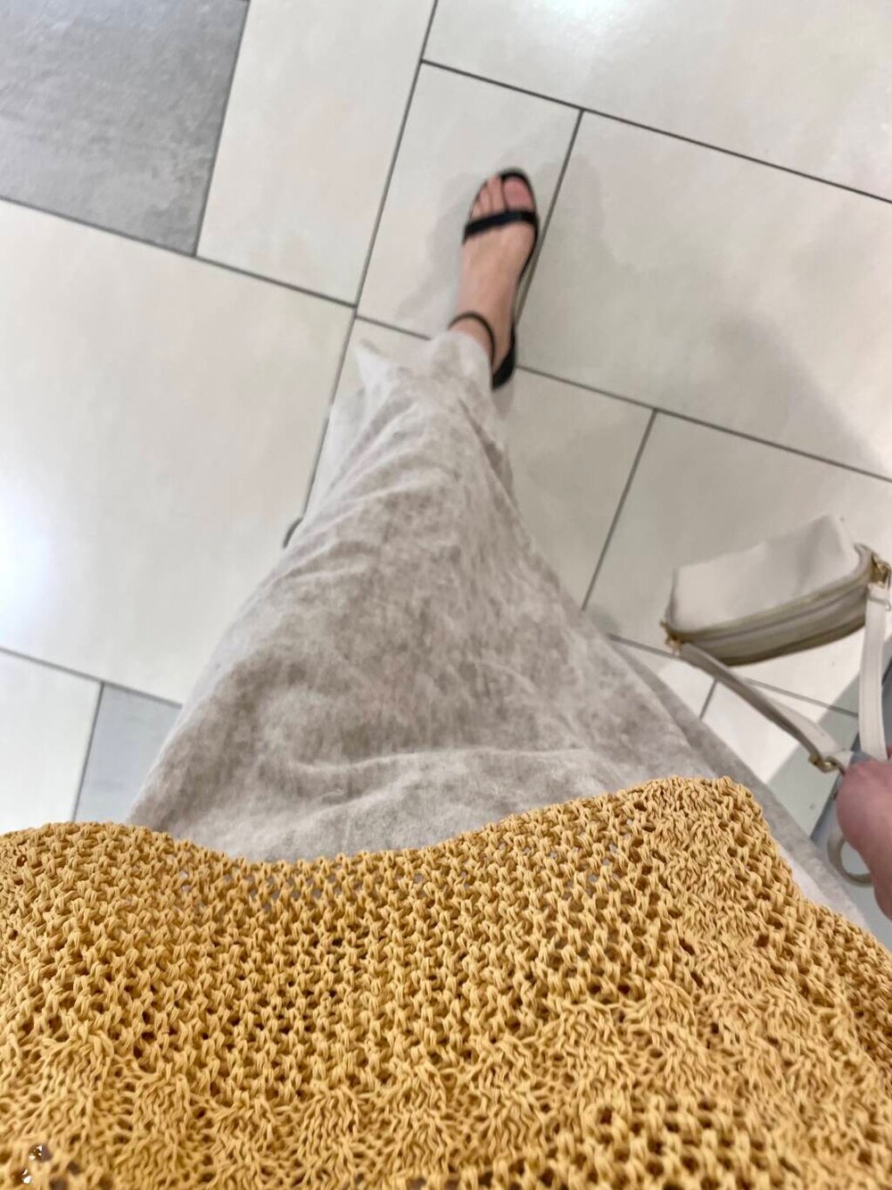 ホワイト系のショルダーバッグ、ベージュ系のスカート、イエロー系のニット/セーターを着用したレディースの冬コーディネートの6枚目の写真