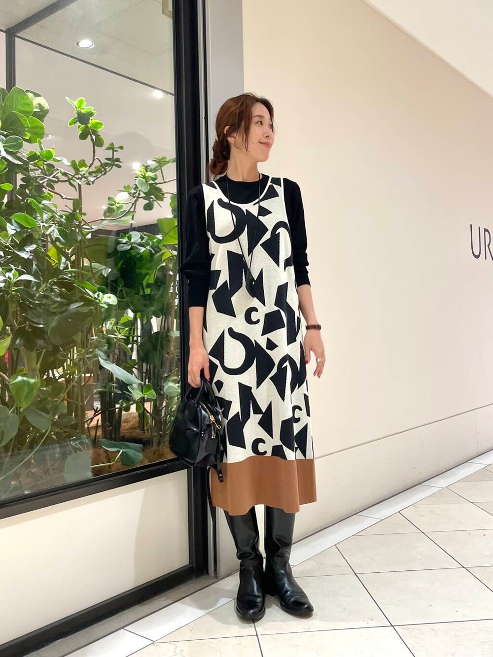 ブラック系のショルダーバッグ、ブラウン系のその他アウター、ホワイト系のニット/セーターを着用したレディースの秋コーディネートの5枚目の写真