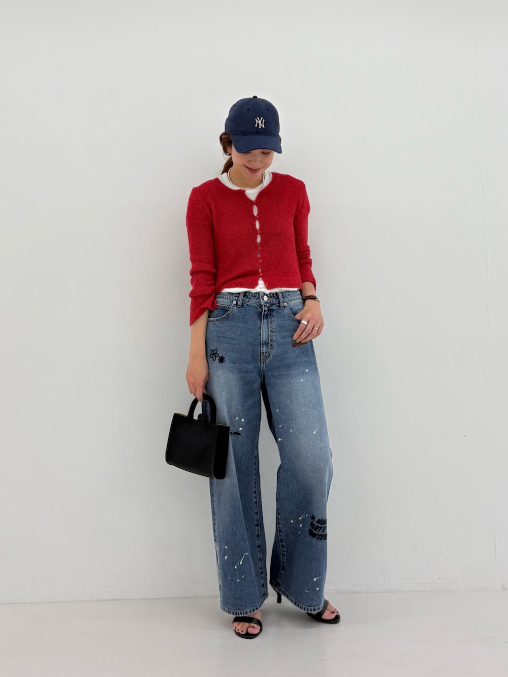 ブルー系のデニムパンツ、ホワイト系のTシャツ/カットソー、ブラック系のハンドバッグを着用したレディースの夏コーディネートの2枚目の写真