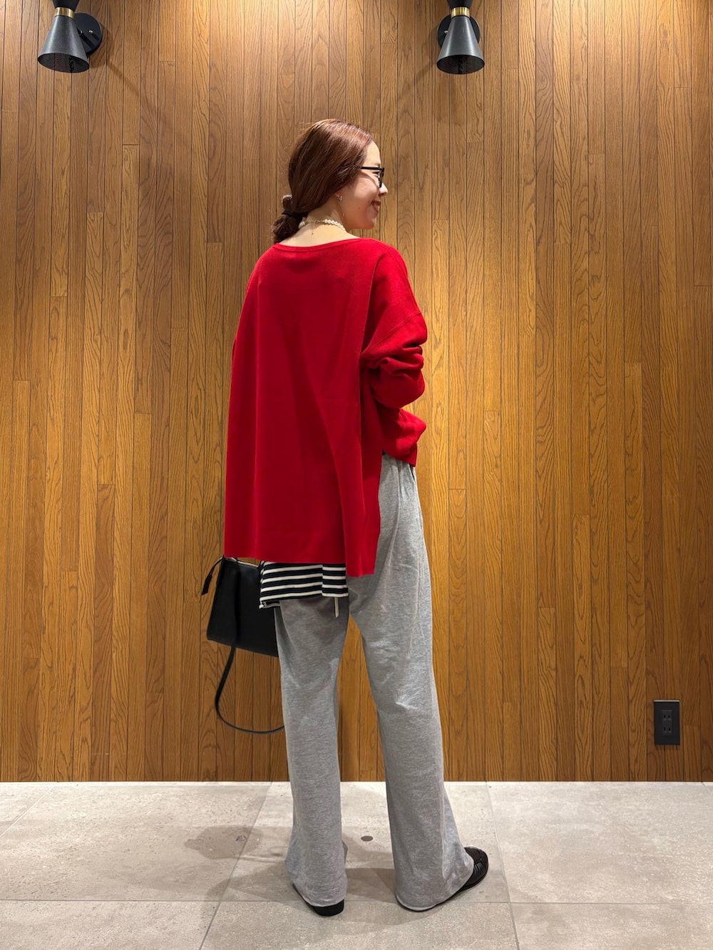 レッド系のニット/セーター、ブルー系のTシャツ/カットソー、グレー系のその他パンツを着用したレディースの秋コーディネートの3枚目の写真