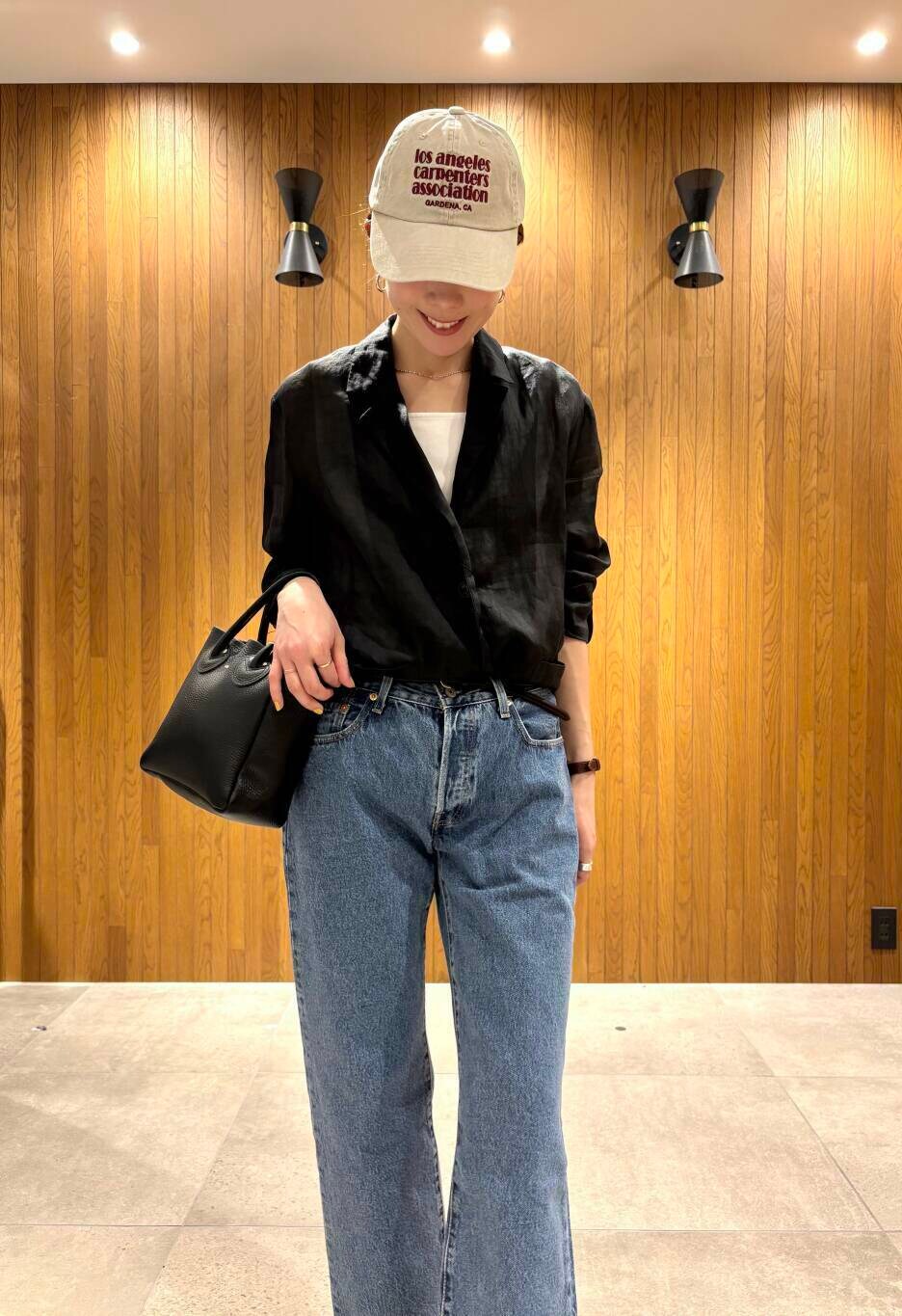 ブラック系のその他アウター、ブルー系のデニムパンツ、ベージュ系のキャップを着用したレディースの春コーディネートの5枚目の写真