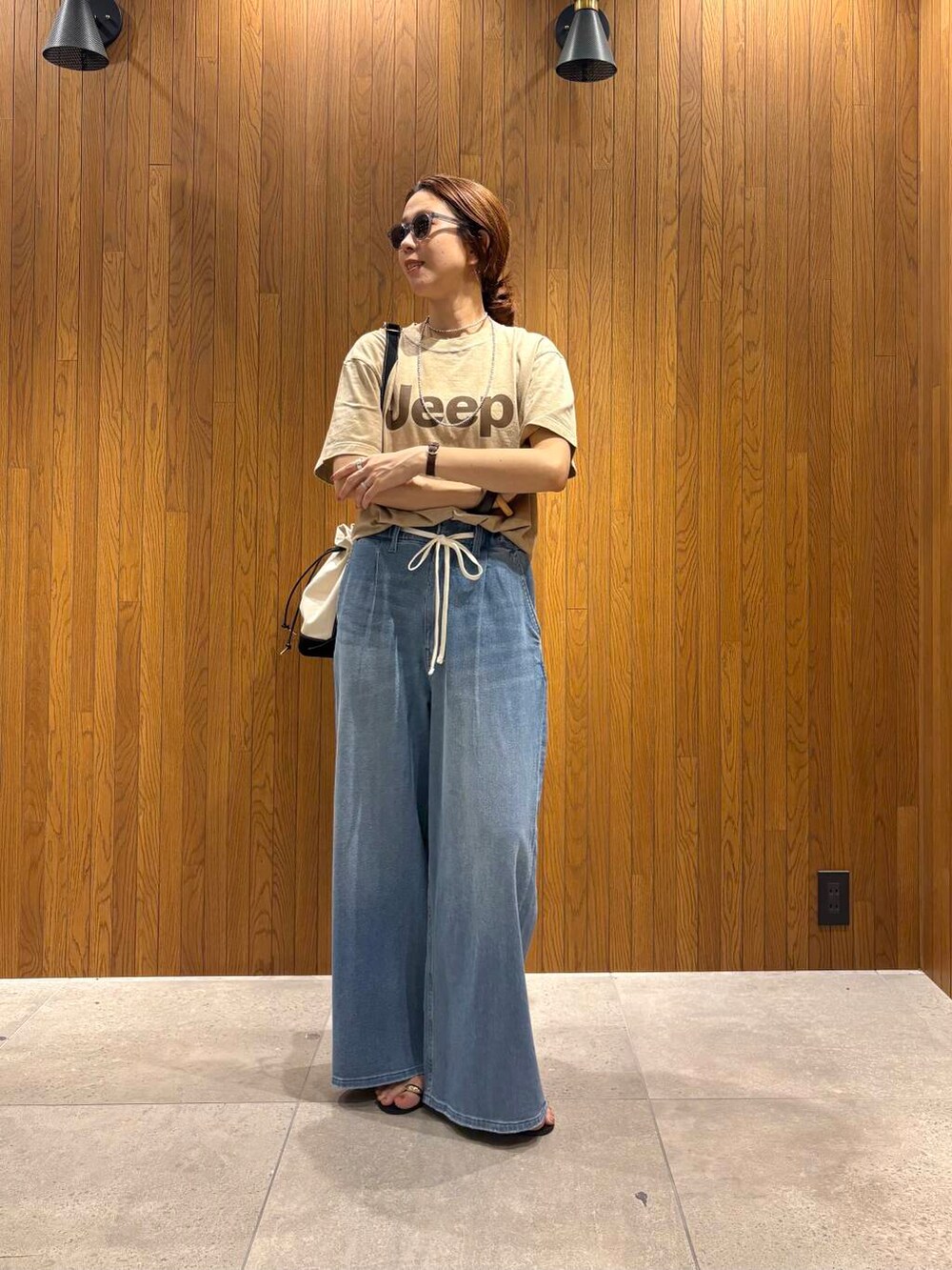 ブルー系のデニムパンツ、ブラック系のサンダル、ベージュ系のTシャツ/カットソーを着用したレディースの夏コーディネートの7枚目の写真