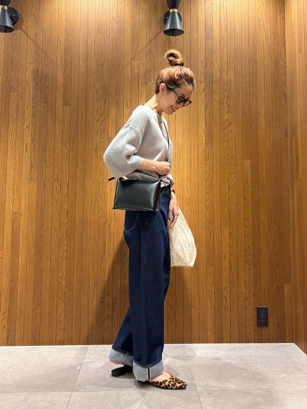 ホワイト系のハンドバッグ、ブルー系のデニムパンツ、ブラック系のショルダーバッグを着用したレディースの秋コーディネートの4枚目の写真