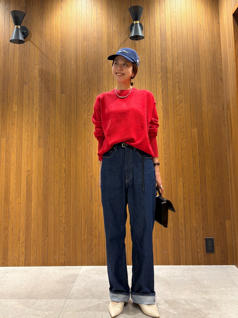 ブルー系のデニムパンツ、レッド系のニット/セーター、ブラック系のハンドバッグを着用したレディースの秋コーディネートの6枚目の写真