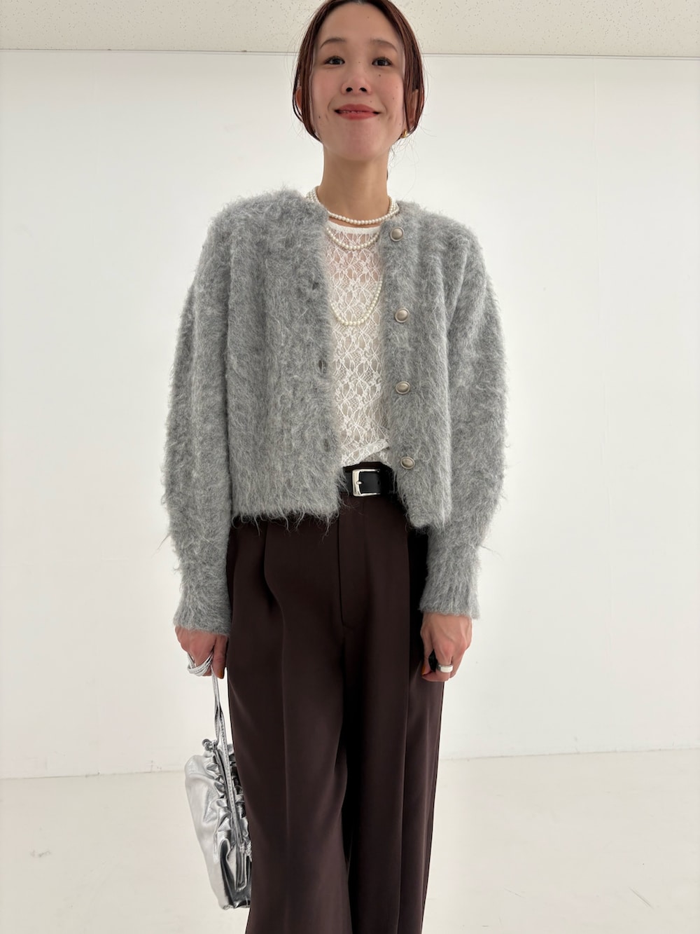 ブラウン系のその他パンツ、グリーン系のカーディガン/ボレロ、シルバー系のショルダーバッグを着用したレディースの秋コーディネートの9枚目の写真