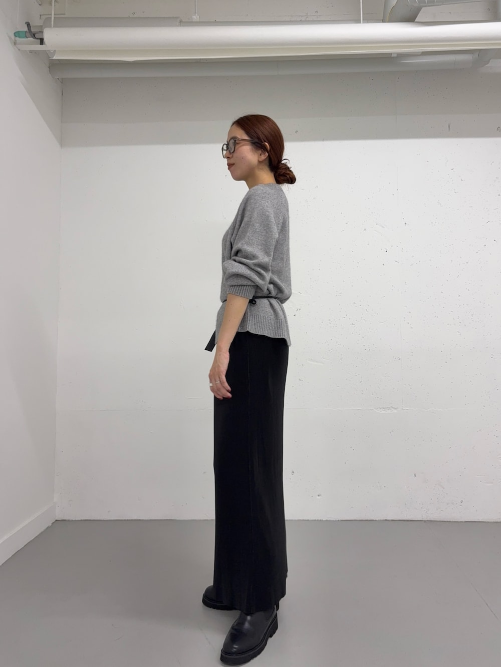 グレー系のニット/セーター、ブラック系のショルダーバッグ、ブラック系のスカートを着用したレディースの秋コーディネートの2枚目の写真