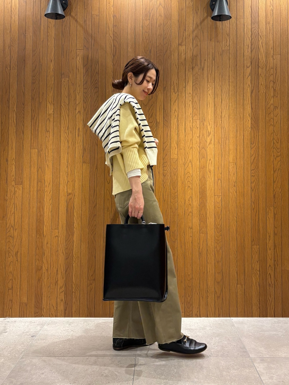 イエロー系のニット/セーター、ベージュ系のその他パンツ、ブラック系のハンドバッグを着用したレディースの冬コーディネートの2枚目の写真