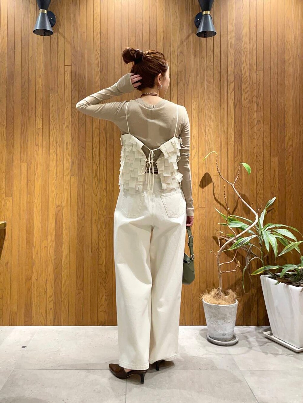 ホワイト系のデニムパンツ、ベージュ系のTシャツ/カットソー、グリーン系のハンドバッグを着用したレディースの冬コーディネートの4枚目の写真