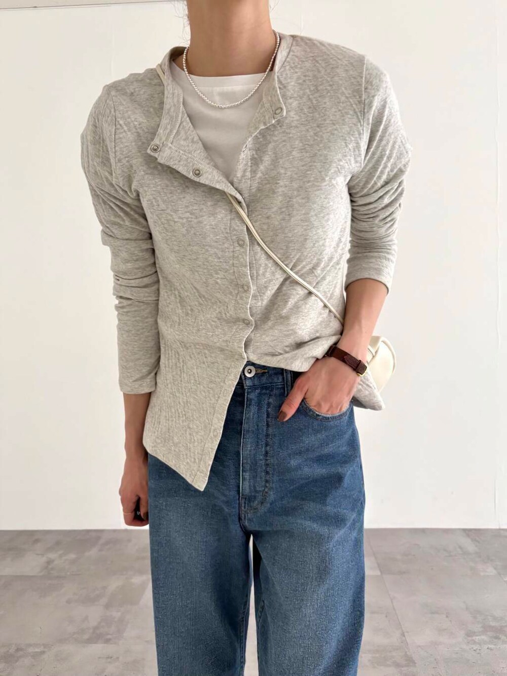 グレー系のカーディガン/ボレロ、ブルー系のデニムパンツ、ホワイト系のショルダーバッグを着用したレディースの春コーディネートの6枚目の写真