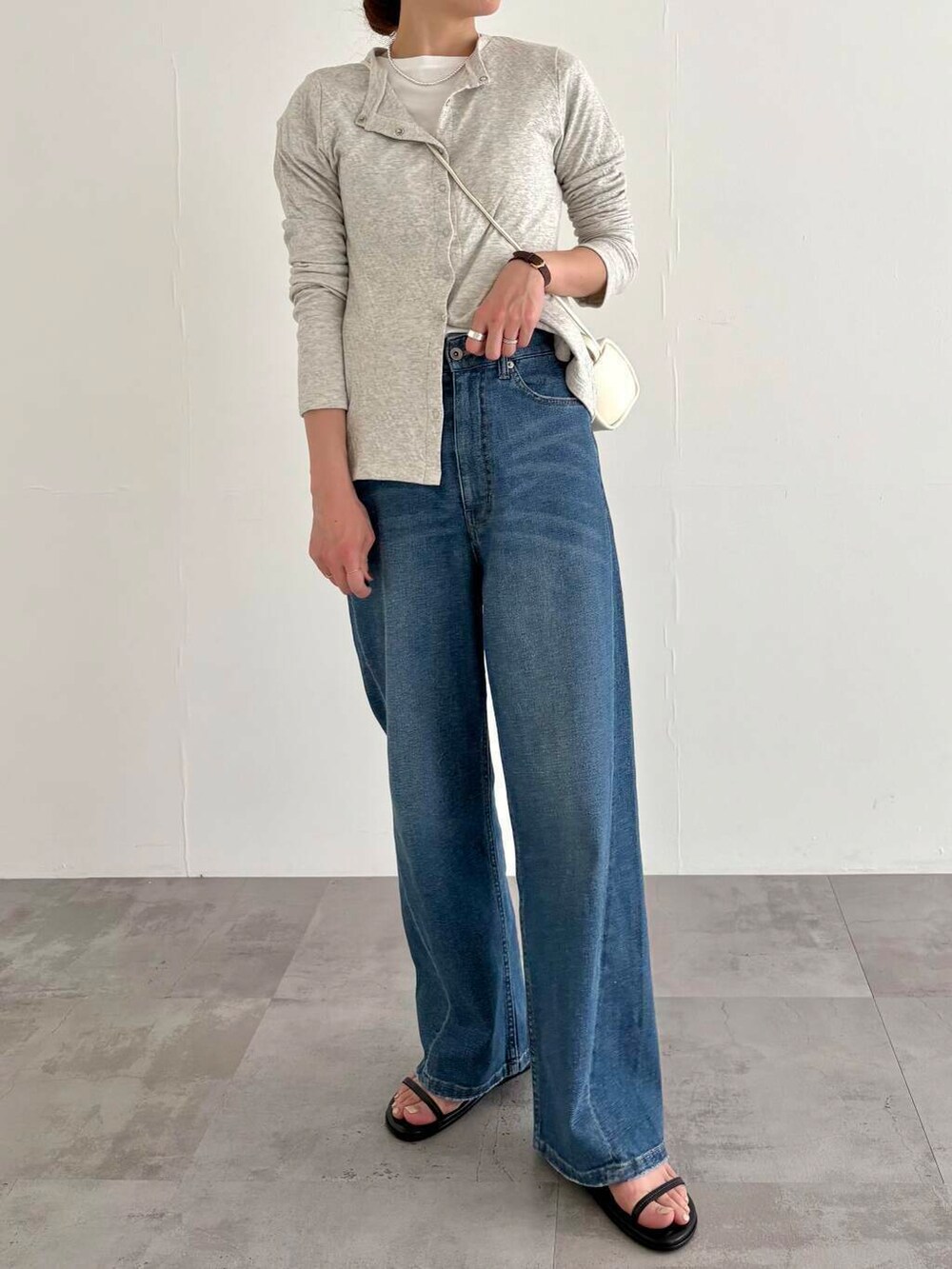 グレー系のカーディガン/ボレロ、ブルー系のデニムパンツ、ホワイト系のショルダーバッグを着用したレディースの春コーディネートの7枚目の写真