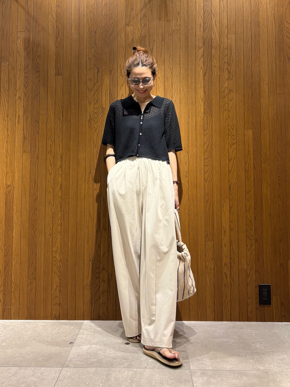 ブラック系のニット/セーター、ホワイト系のその他パンツ、ホワイト系のハンドバッグを着用したレディースの春コーディネートの4枚目の写真
