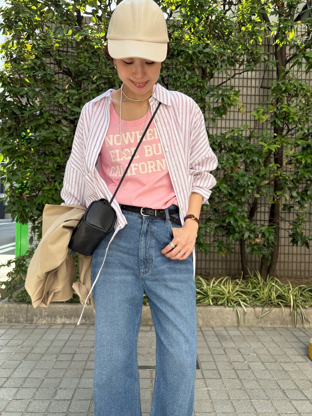 レッド系のシャツ/ブラウス、ベージュ系のトレンチコート、ブルー系のデニムパンツを着用したレディースの春コーディネートの7枚目の写真