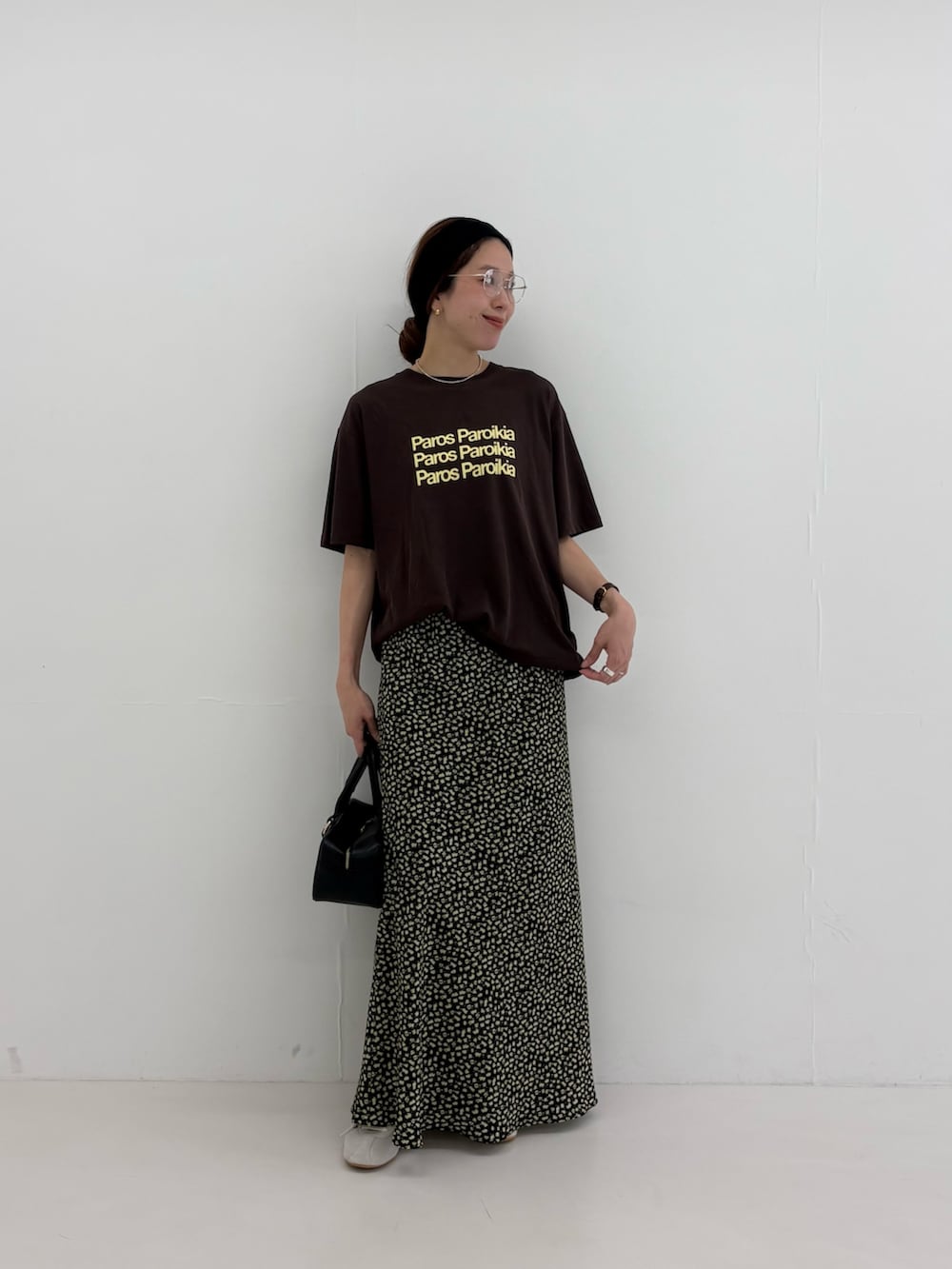 ブラウン系のTシャツ/カットソー、イエロー系のスカート、ブラック系のハンドバッグを着用したレディースの夏コーディネートの4枚目の写真