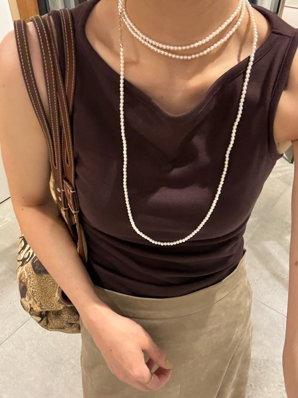 ベージュ系のスカート、ベージュ系のトートバッグ、ブラック系のサンダルを着用したレディースの夏コーディネートの6枚目の写真