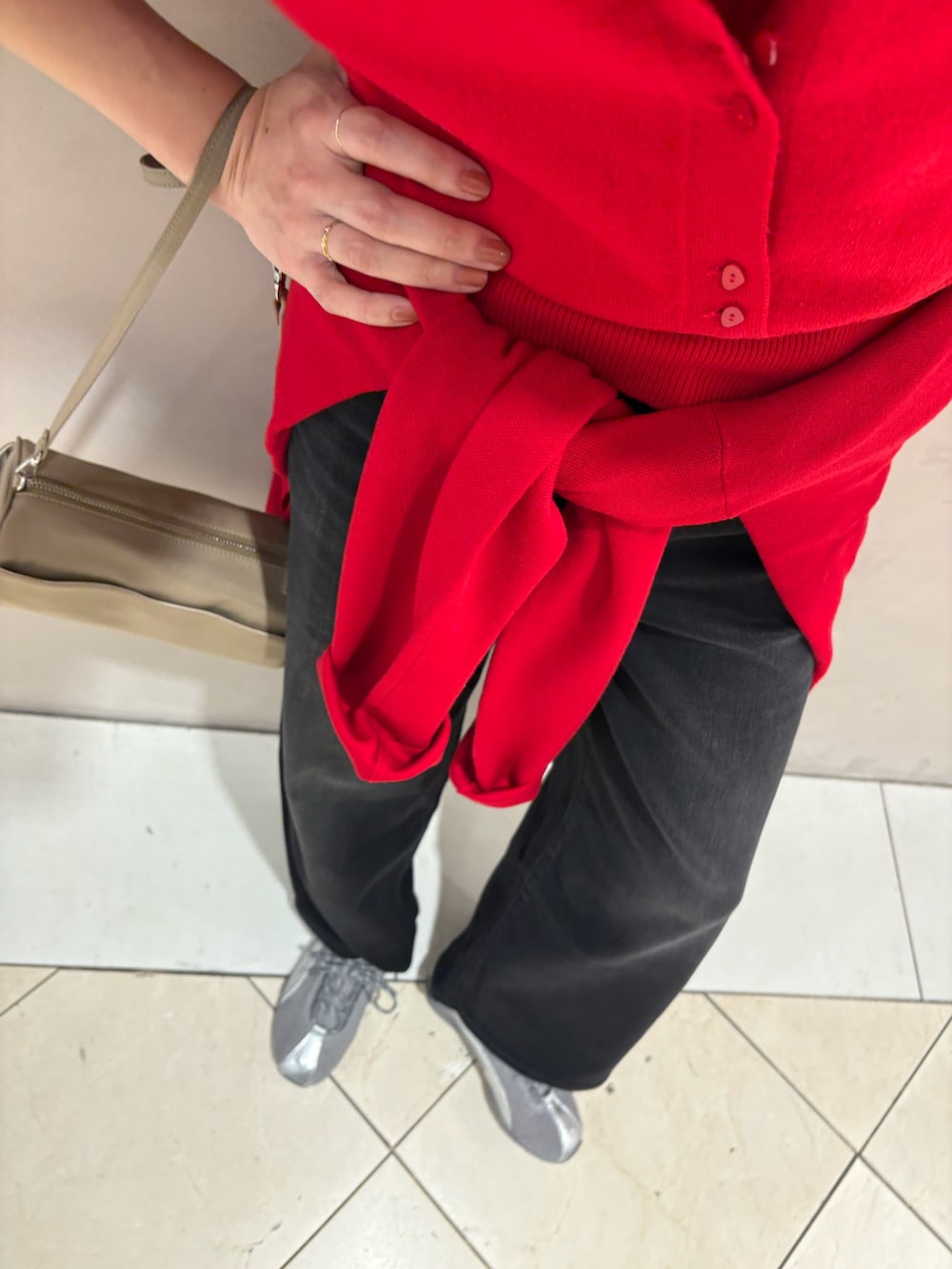 レッド系のニット/セーター、ブラック系のデニムパンツ、グレー系のスニーカーを着用したレディースの秋コーディネートの8枚目の写真