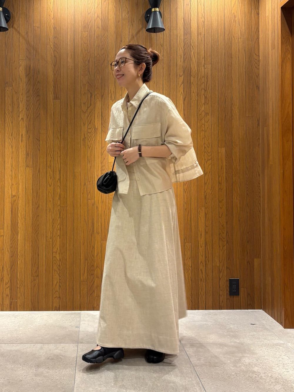 ベージュ系のスカート、ホワイト系のシャツ/ブラウス、ブラック系のショルダーバッグを着用したレディースの春コーディネートの2枚目の写真