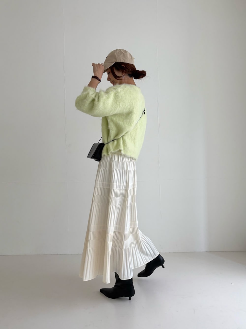 ホワイト系のスカート、グリーン系のカーディガン/ボレロ、ブラック系のブーツを着用したレディースの秋コーディネートの4枚目の写真