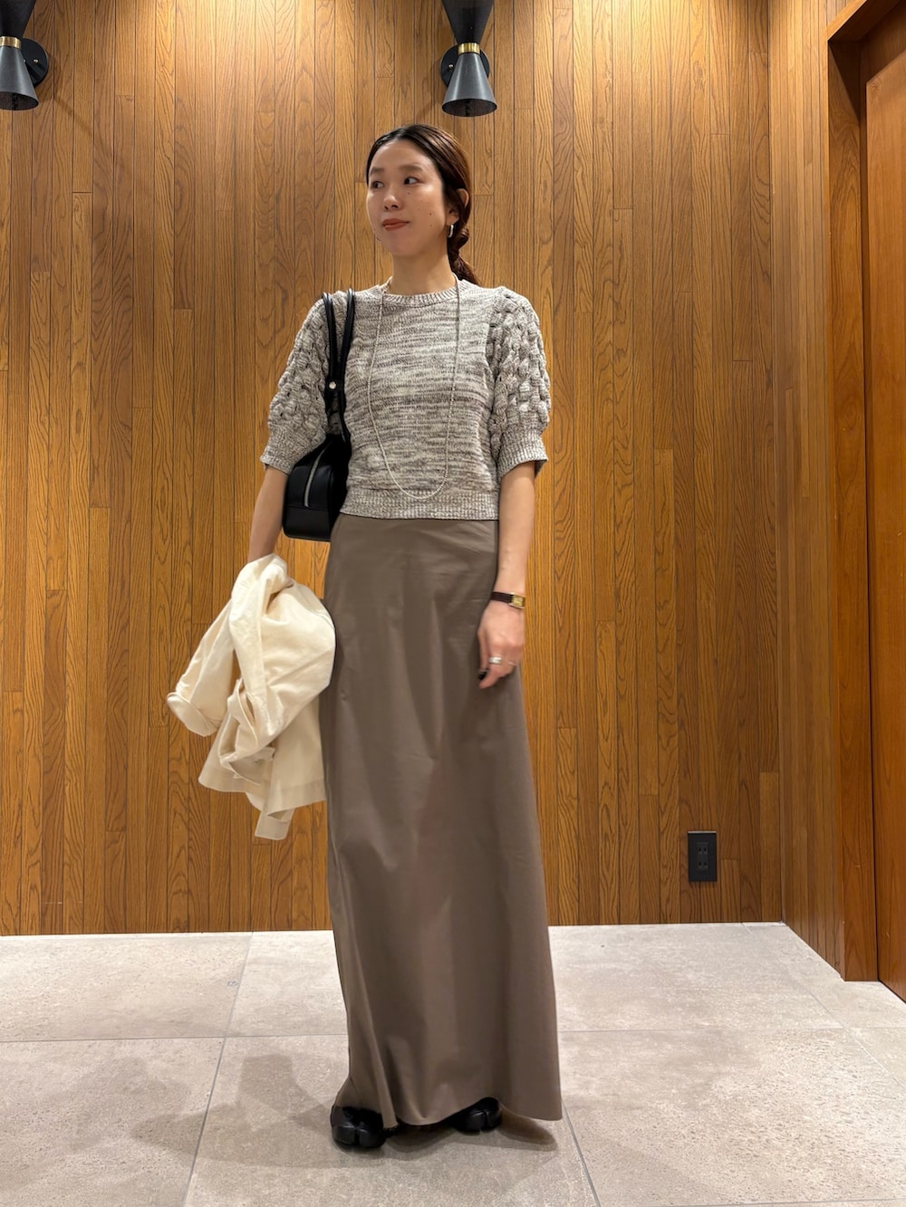 グレー系のスカート、その他のニット/セーター、ブラック系のスニーカーを着用したレディースの春コーディネートの8枚目の写真