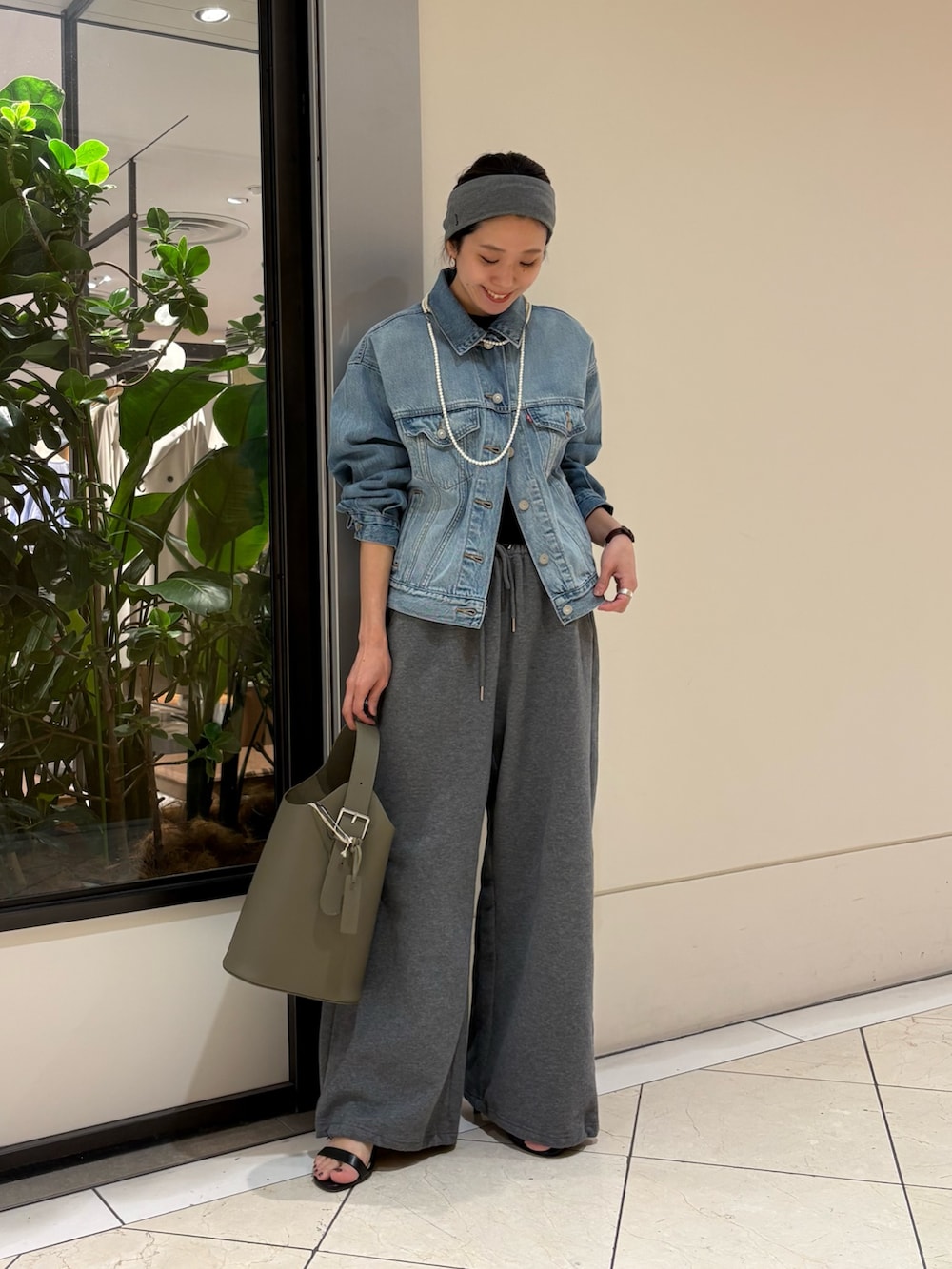 ブルー系のデニムジャケット、グリーン系のハンドバッグ、グレー系のヘアバンドを着用したレディースの春コーディネートの5枚目の写真