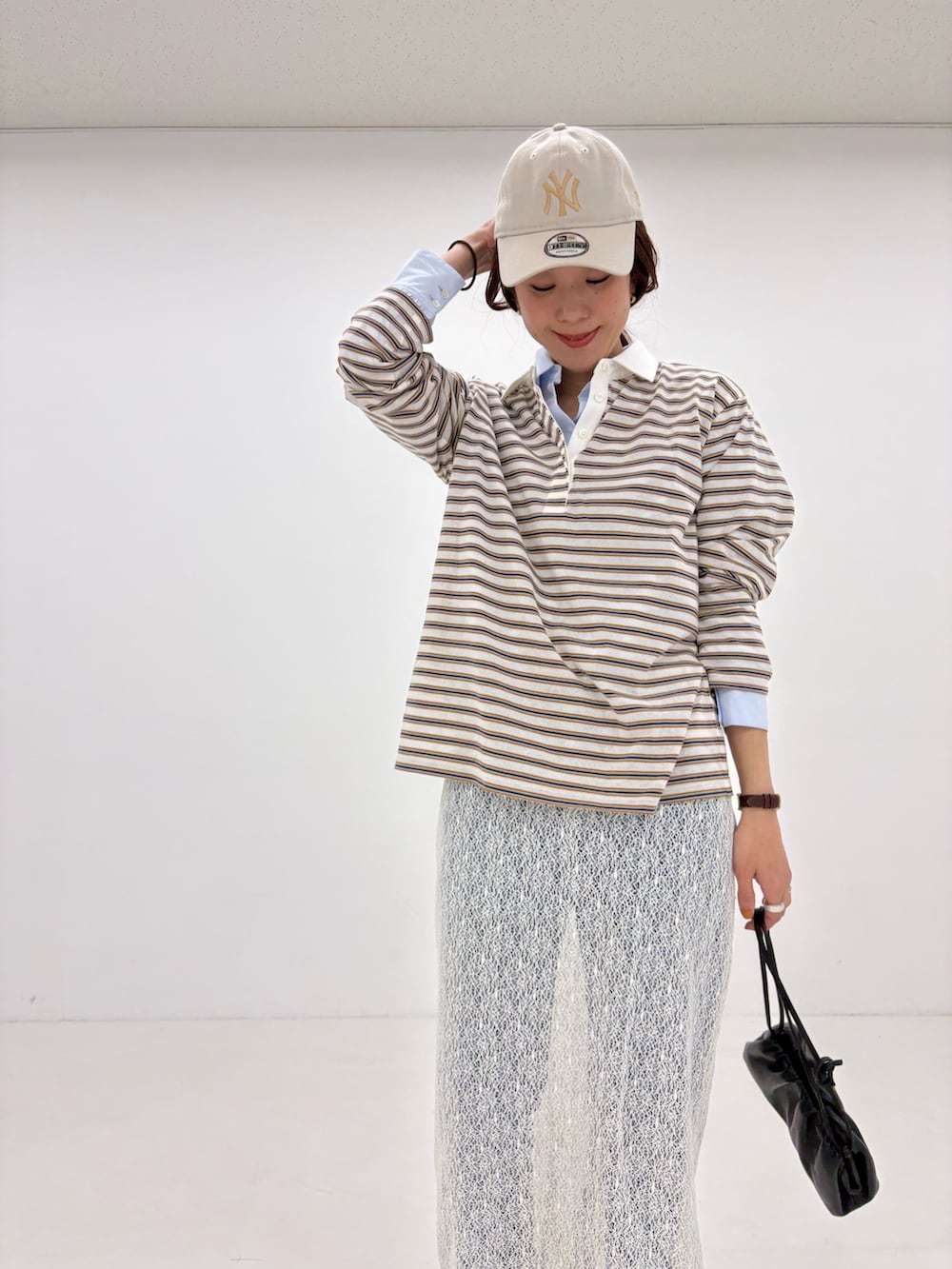 ホワイト系のスカート、ベージュ系のトレンチコート、ホワイト系のスニーカーを着用したレディースの春コーディネートの7枚目の写真