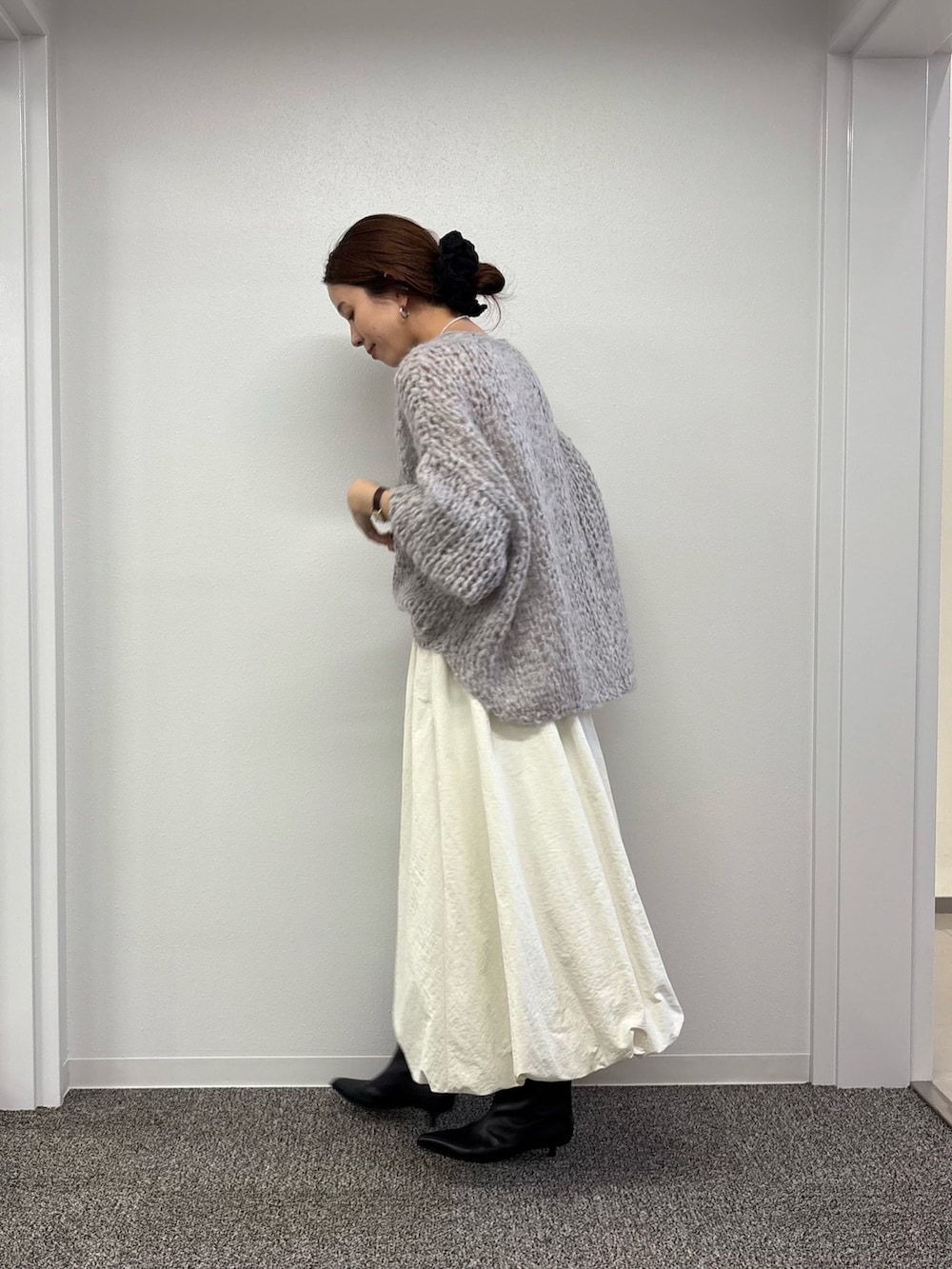 ホワイト系のスカート、ブラック系のブーツ、グレー系のニット/セーターを着用したレディースの秋コーディネートの2枚目の写真