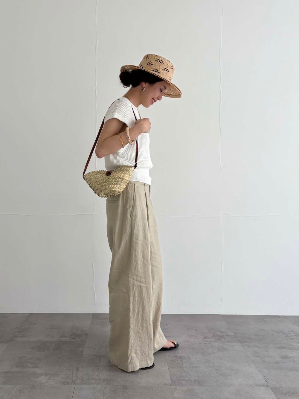 ベージュ系のその他パンツ、ホワイト系のベスト、ブラック系のサンダルを着用したレディースの夏コーディネートの2枚目の写真