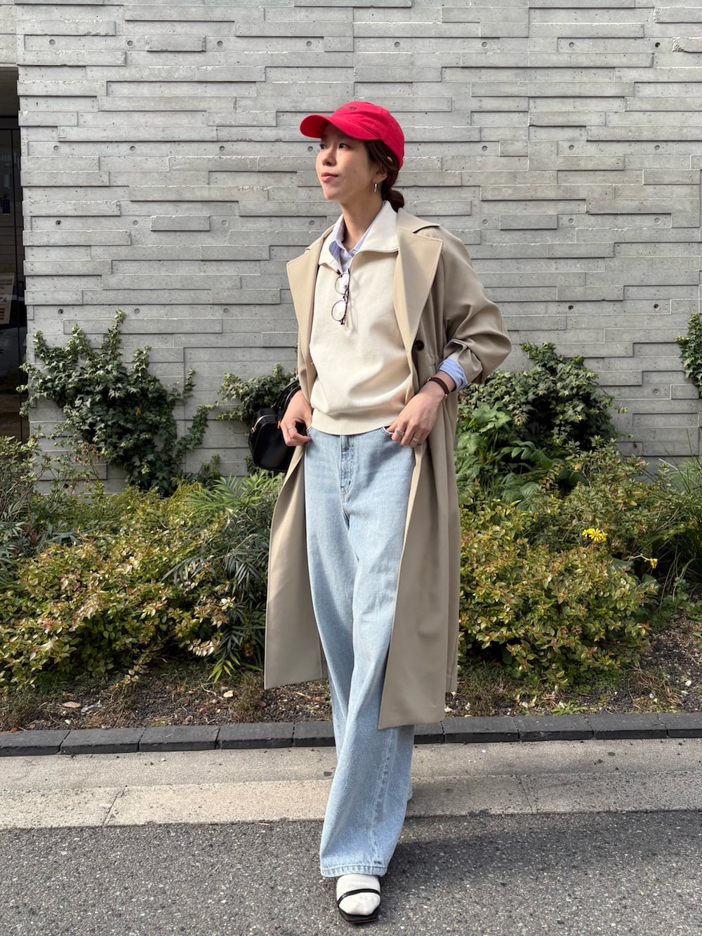 ベージュ系のトレンチコート、グレー系のデニムパンツ、ブラック系のショルダーバッグを着用したレディースの冬コーディネートの2枚目の写真