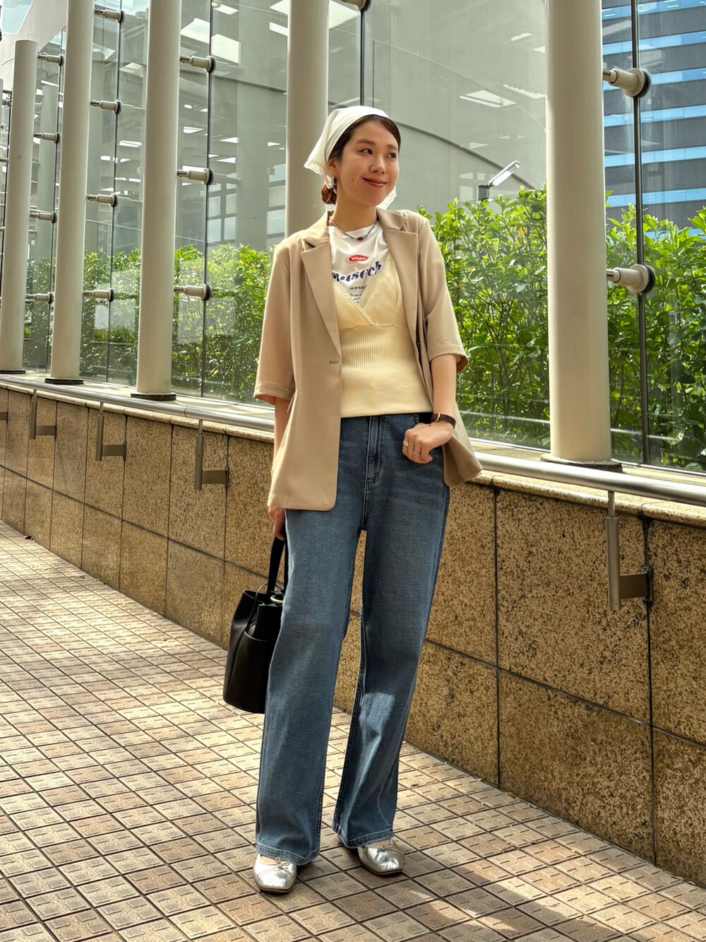 ブルー系のデニムパンツ、ベージュ系のその他アウター、ブラック系のハンドバッグを着用したレディースの春コーディネートの5枚目の写真