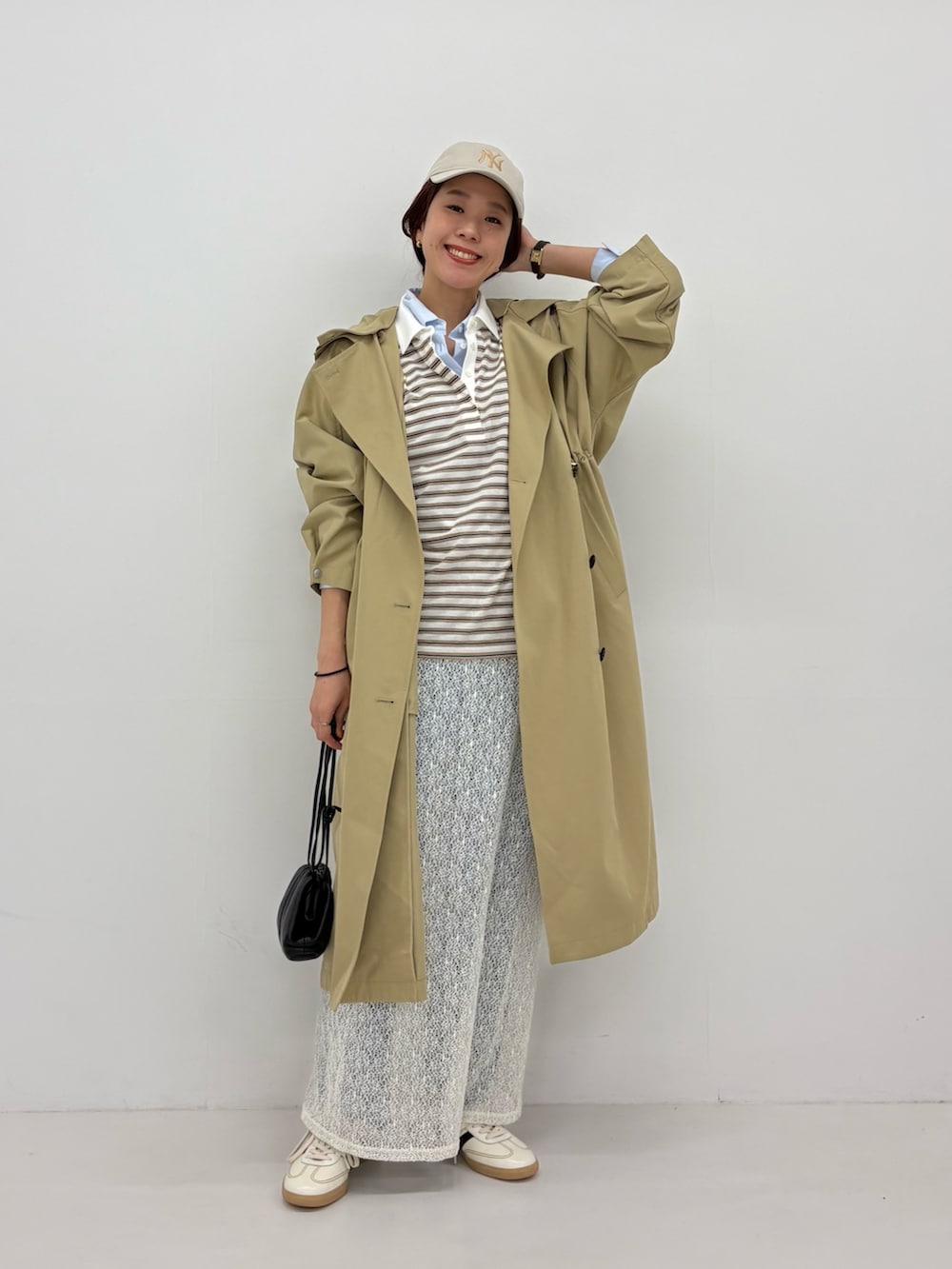 ホワイト系のスカート、ベージュ系のトレンチコート、ホワイト系のスニーカーを着用したレディースの春コーディネートの5枚目の写真